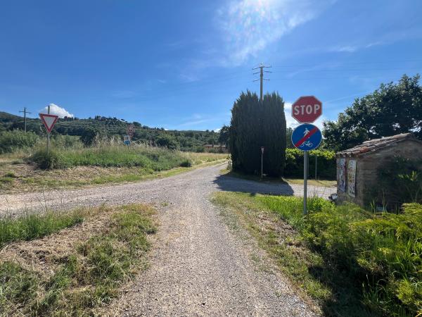 Carrefour entre des pistes en gravier avec panneau d'arrêt et signal indiquant la fin de la piste cyclable/piétonne